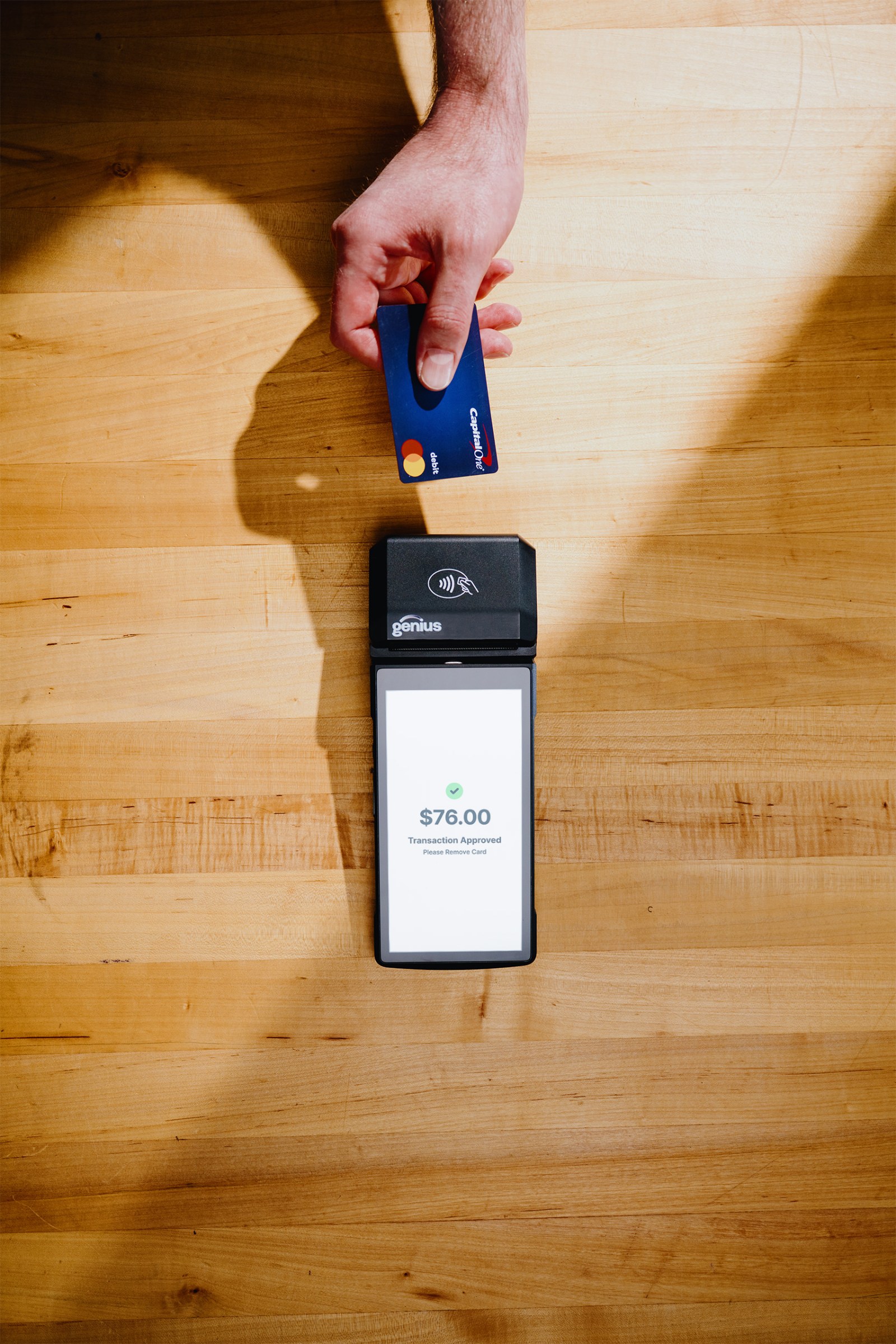 A guest tapping a card on the Genius Mobile 2.5 handheld