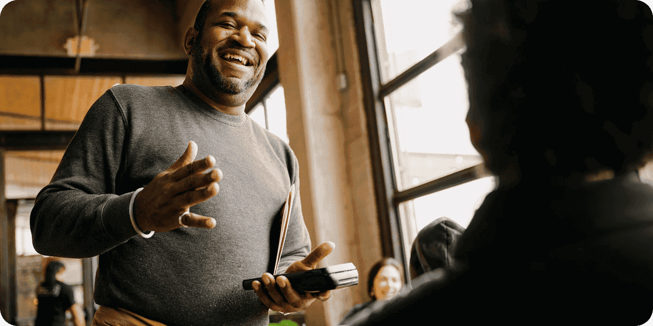 A server talks with a guest while holding a handheld Point of Sale terminal