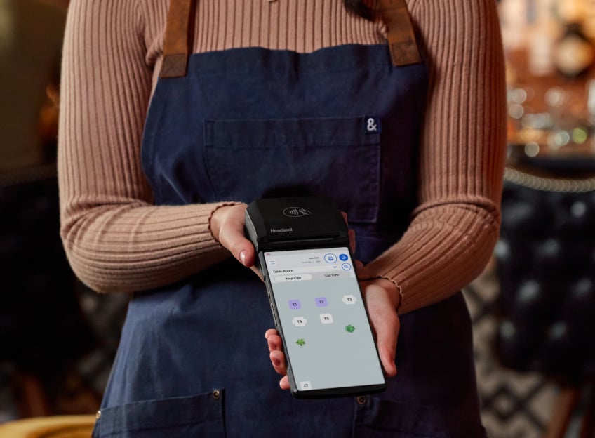 A server presenting a handheld terminal to a guest at a table