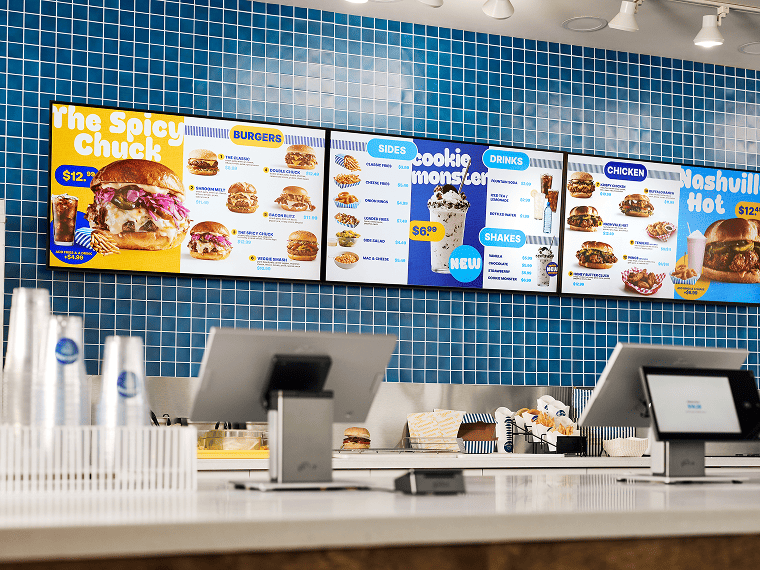 Digital menu boards above a quick-service counter