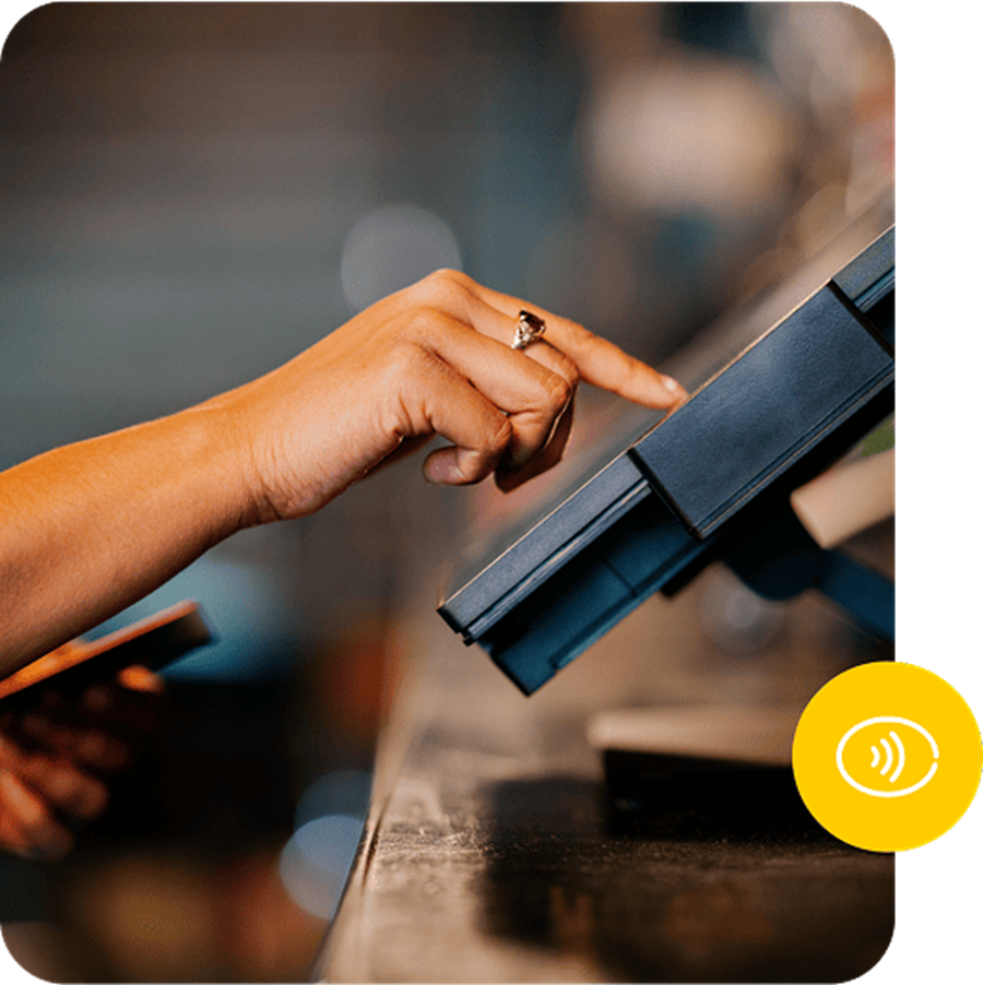 A guest tapping a card on a Genius terminal at the bar