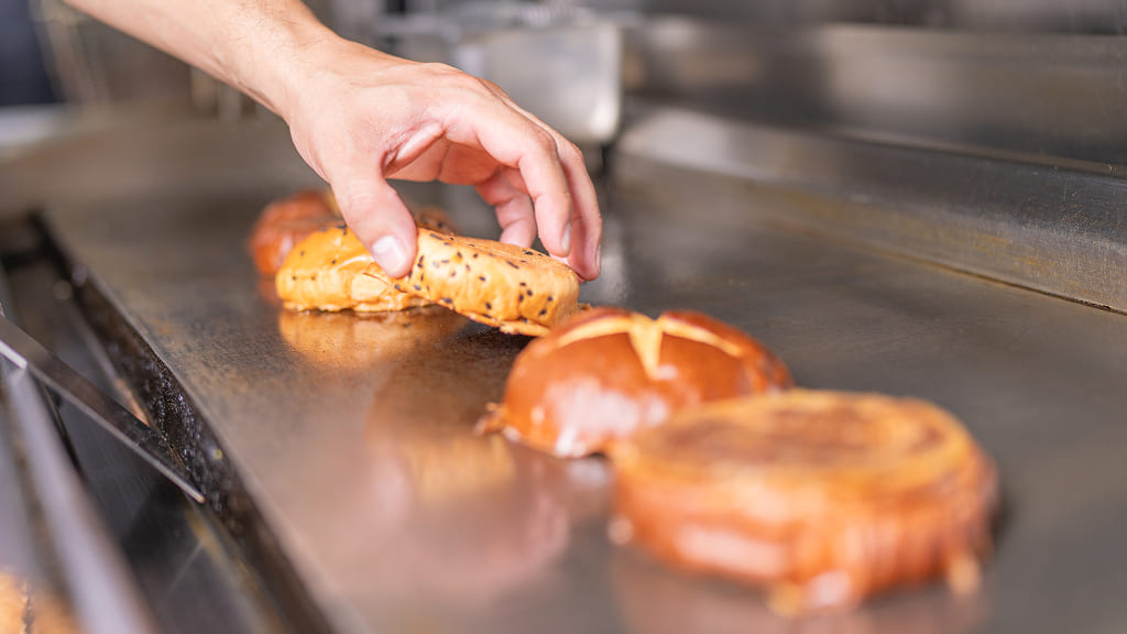 Burger buns toasting on a stainless griddle