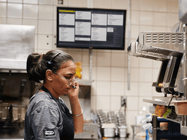 A back of house worker reading tickets on a kitchen display screen