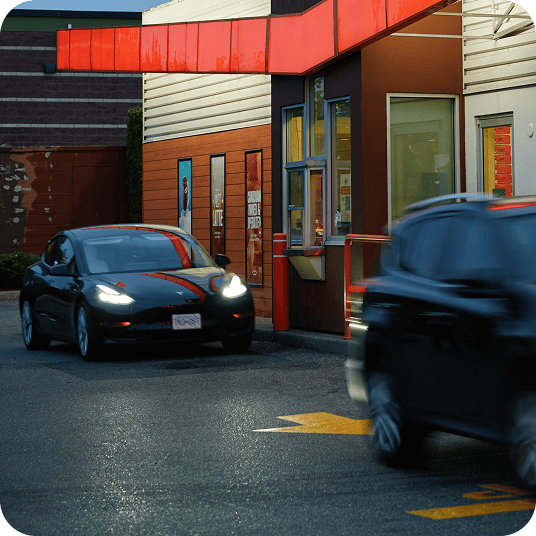 Two cars in a drive thru at a quick service restaurant