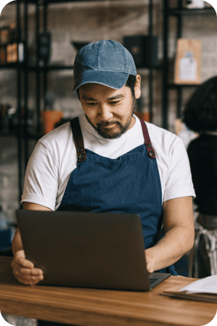 A shop owner reviewing invoices on a laptop