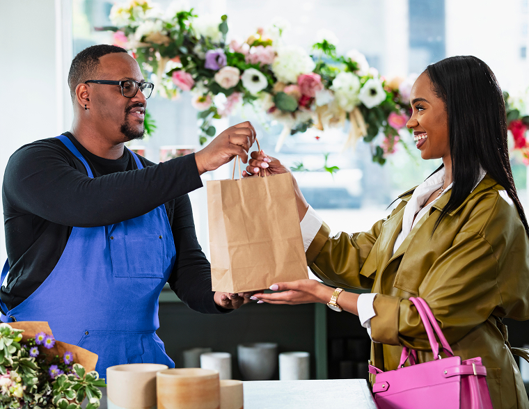 A florist handing a wrapped purchase to a customer